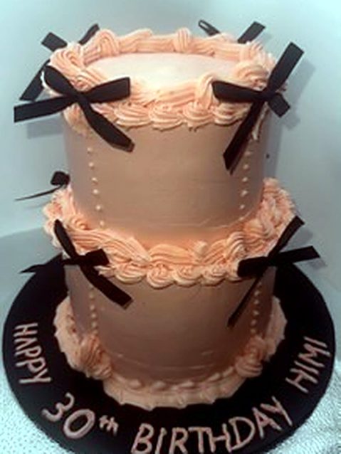 Two-tier pink 30th birthday cake with bows