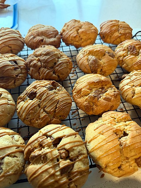 Caramel-drizzled choc-chunk cookies on a cooling rack